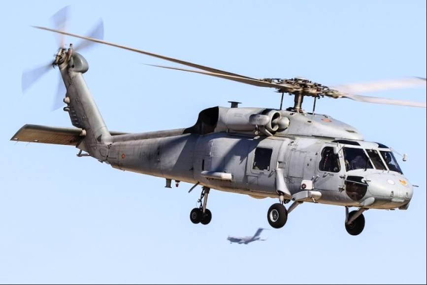 Un SH-60F en vuelo estacionario, debajo de este se ve aterrizando un C.17 de la Fuerza A