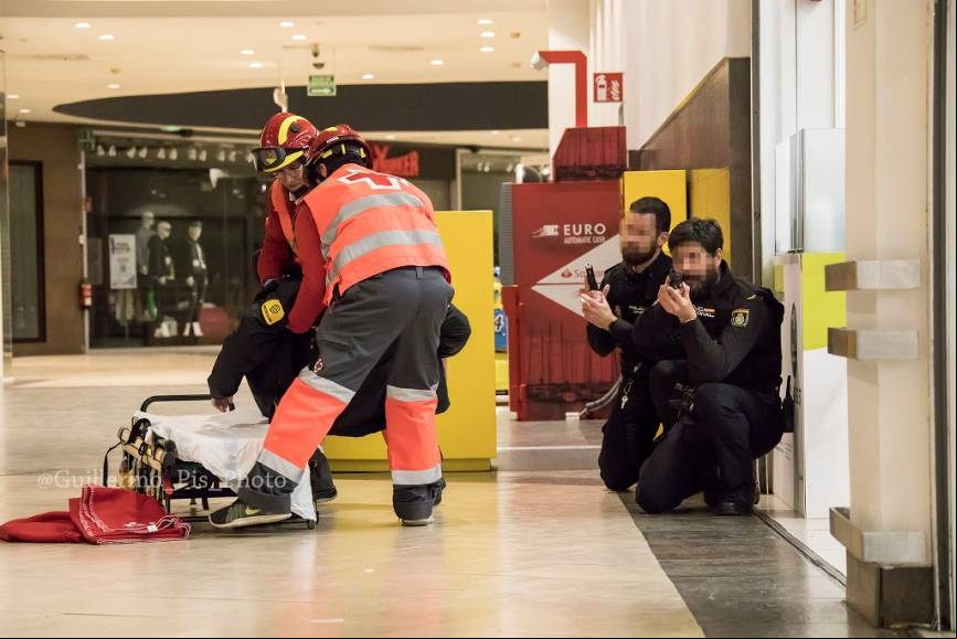 Una vez asegurada la zona, los equipos sanitarios socorren a los heridos bajo la cobertura de agentes del CNP , pues la amenaza continua en el interior del Hipermercado.
